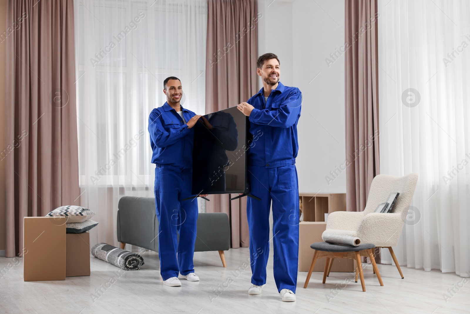 Photo of Male movers carrying plasma TV in new house