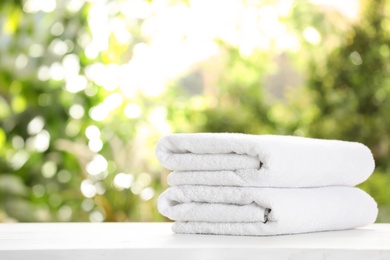 Photo of Stack of clean soft towels on table against blurred background. Space for text