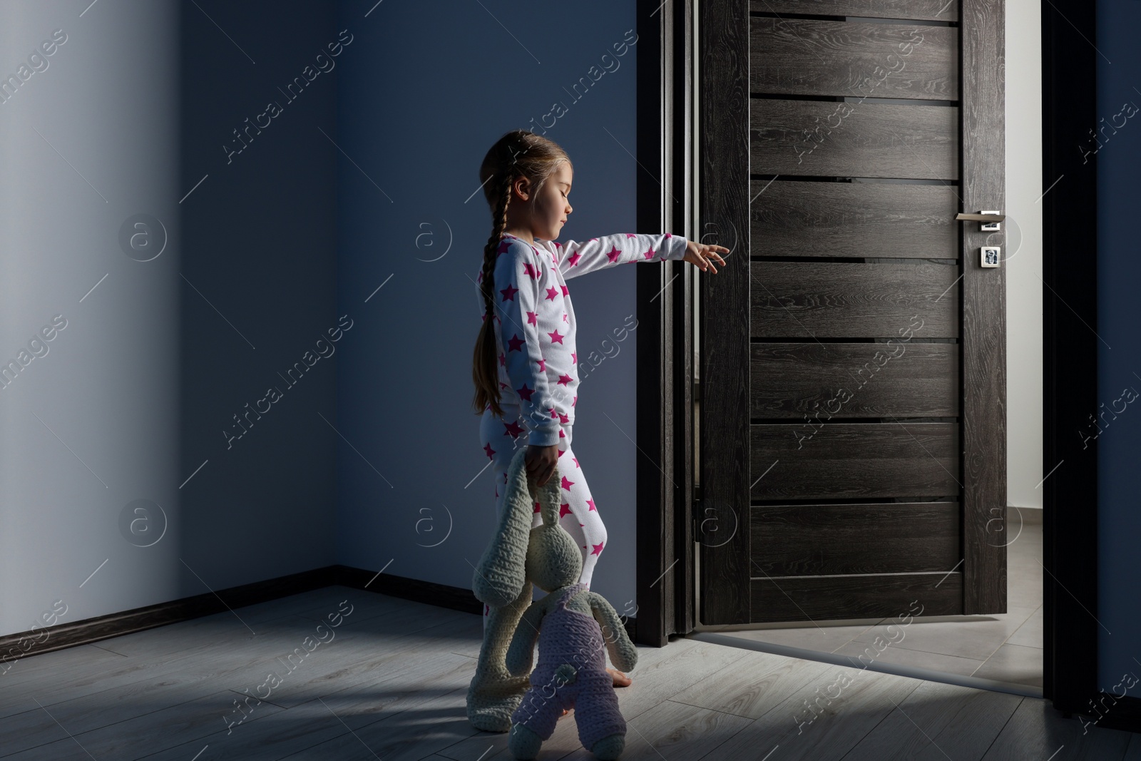 Photo of Girl in pajamas with toy bunny sleepwalking indoors at night