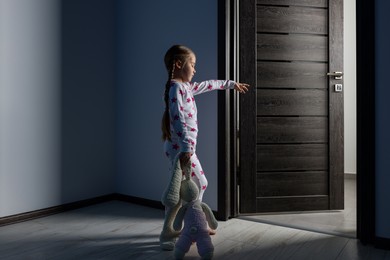 Photo of Girl in pajamas with toy bunny sleepwalking indoors at night