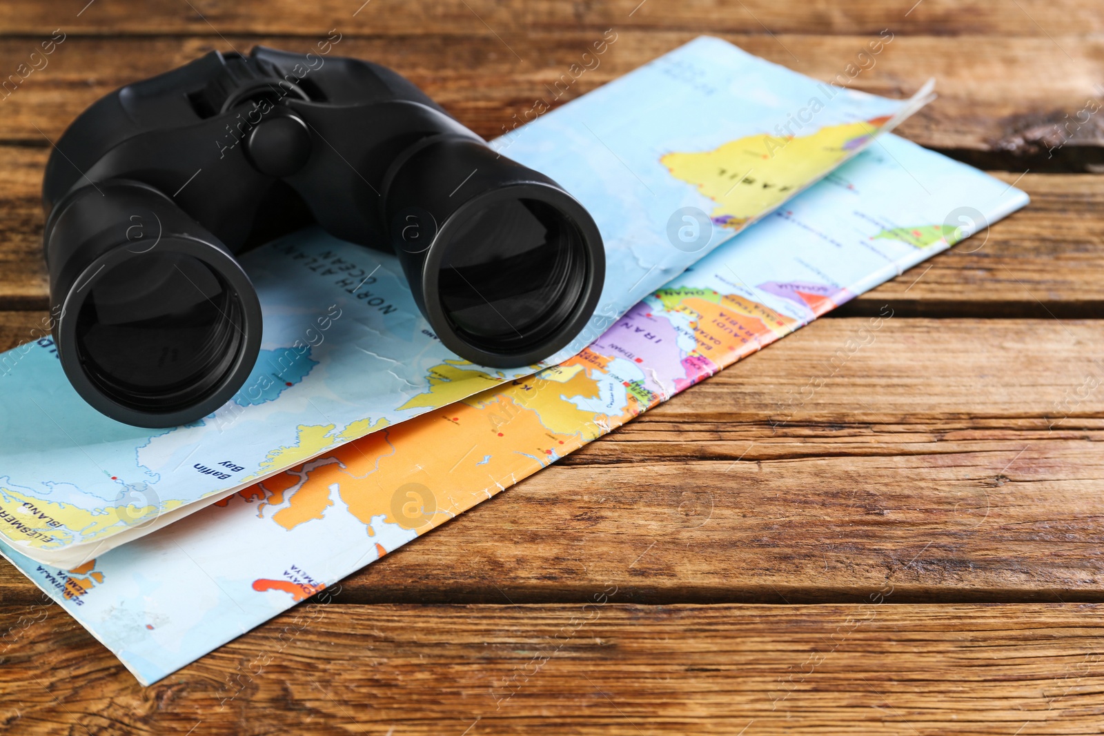 Photo of Modern binoculars and map on wooden table, space for text