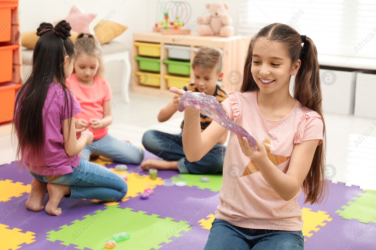 Photo of Preteen girl playing with slime in room