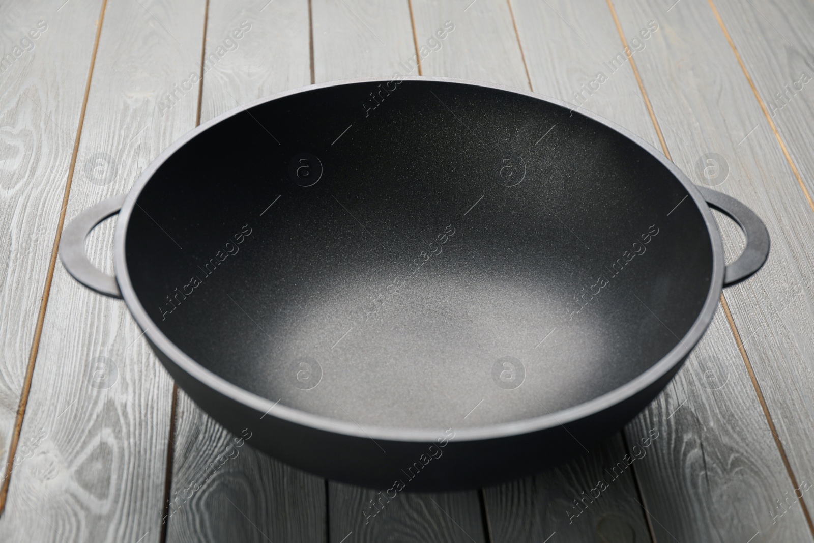 Photo of Empty iron wok on grey wooden table. Chinese cookware