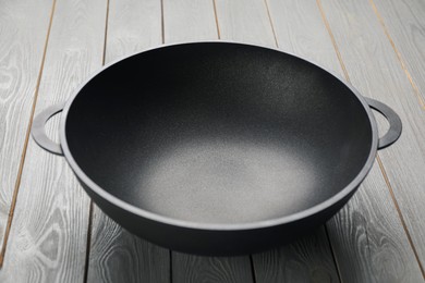 Empty iron wok on grey wooden table. Chinese cookware