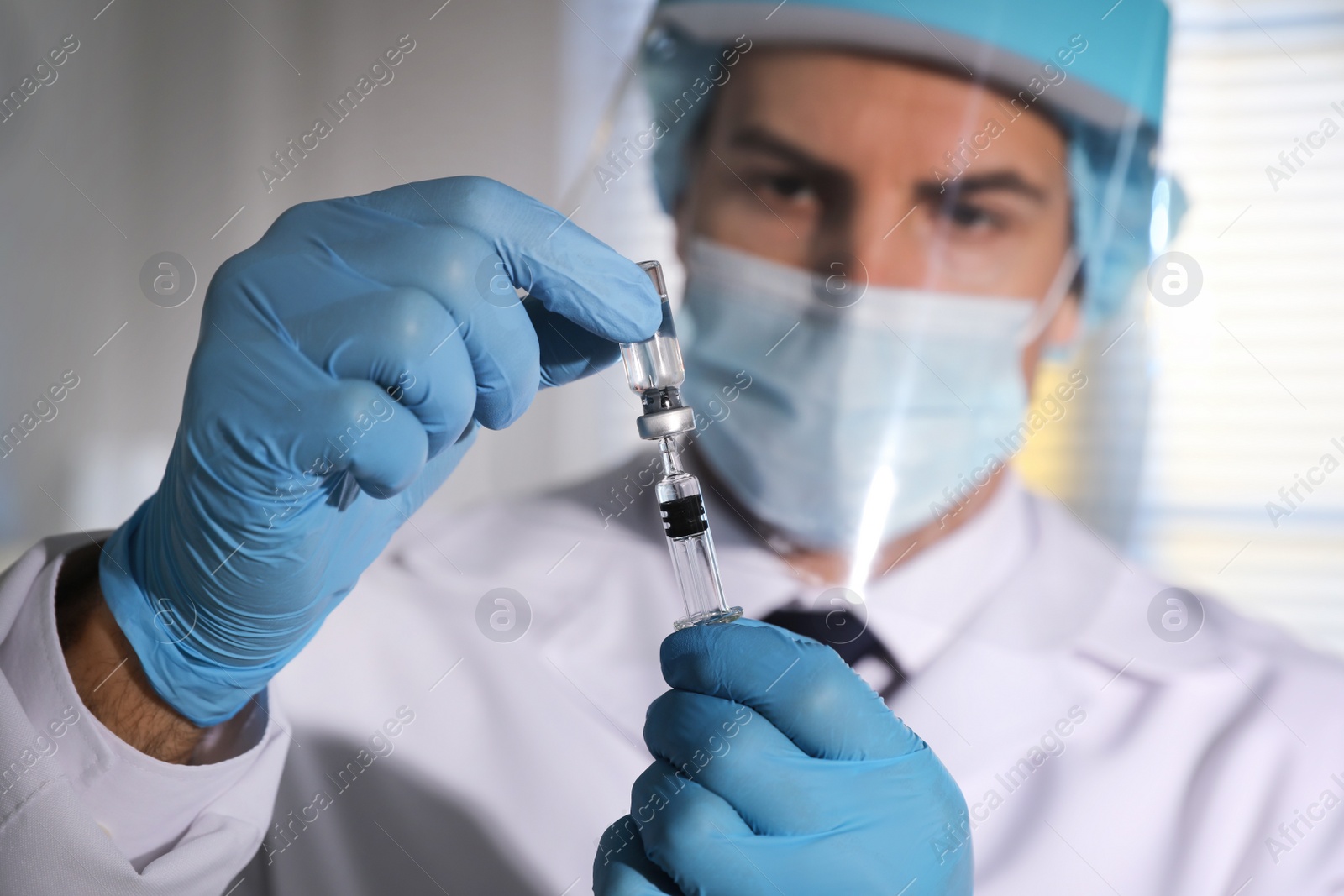 Photo of Doctor filling syringe with vaccine against Covid-19 in laboratory, focus on hands