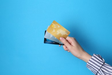 Photo of Woman holding credit cards on light blue background, closeup