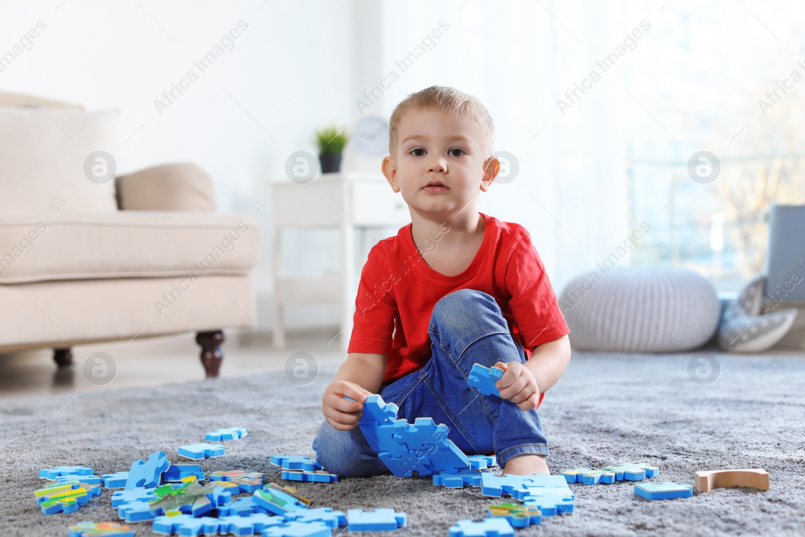 Photo of Cute little child playing with puzzles on floor indoors