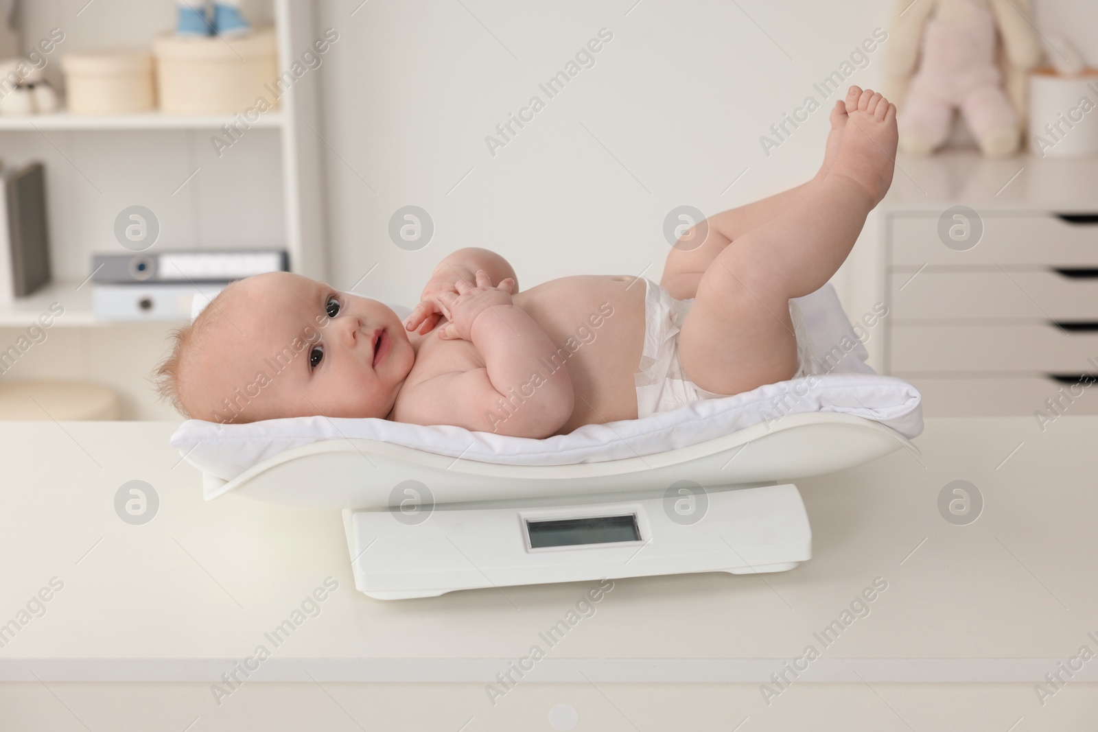 Photo of Cute little baby lying on scales in clinic