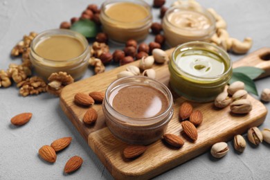 Photo of Jars with butters made of different nuts and ingredients on grey table