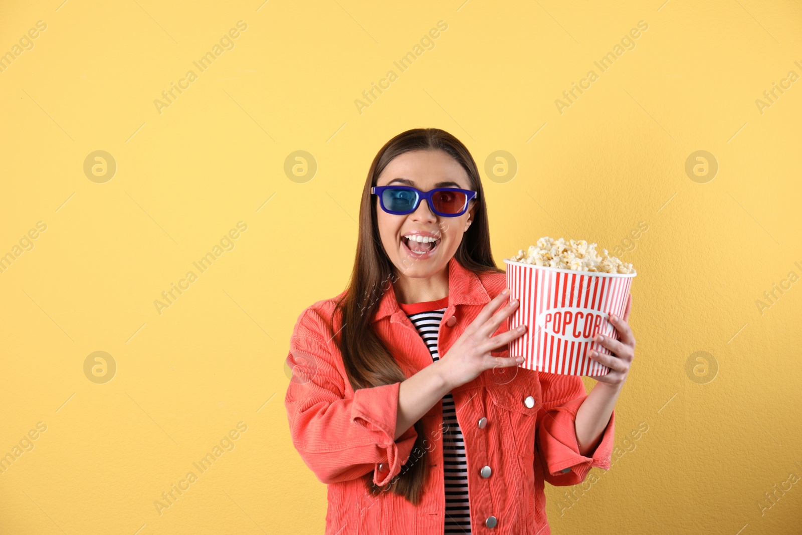 Photo of Emotional woman with 3D glasses and tasty popcorn on color background