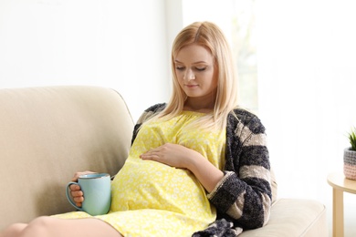 Beautiful pregnant woman resting on sofa at home