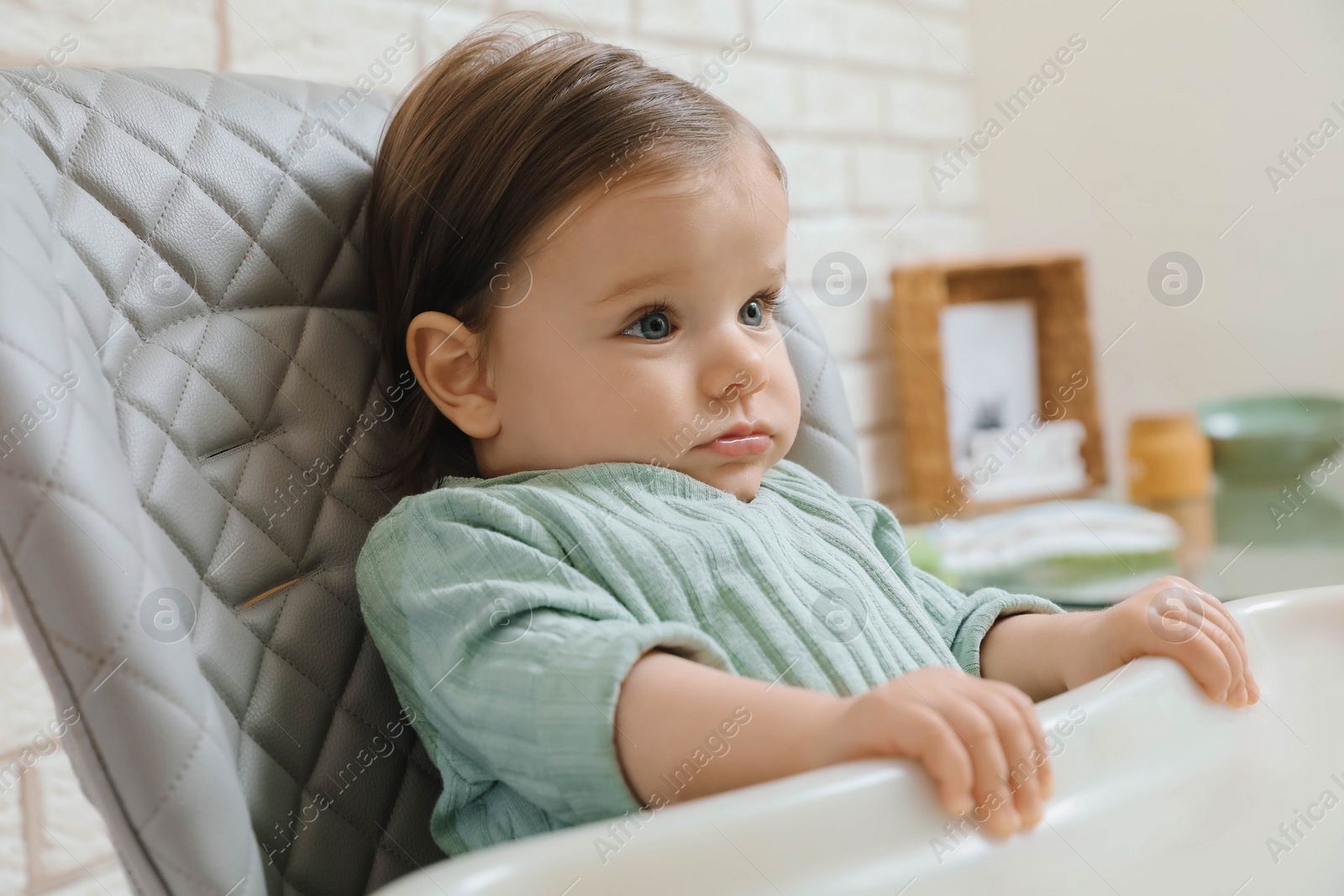 Photo of Cute little baby sitting in high chair indoors