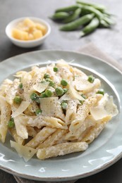 Delicious pasta with green peas, cheese and creamy sauce on table