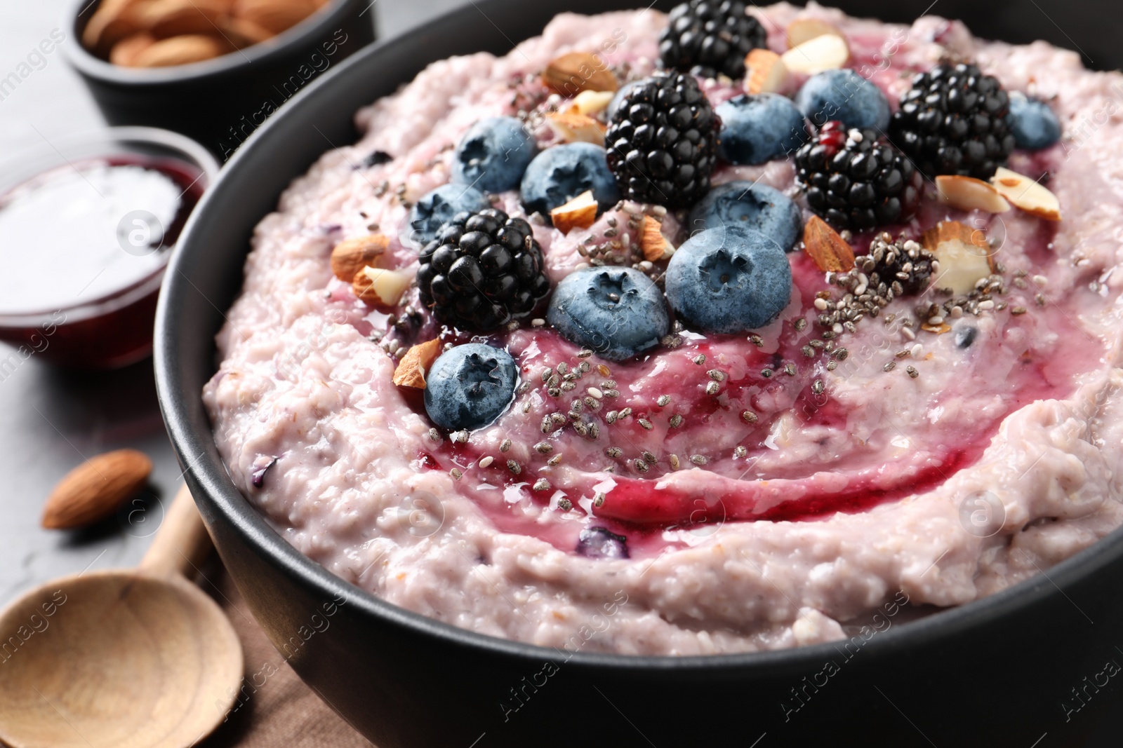 Photo of Tasty oatmeal porridge with toppings in bowl on table, closeup