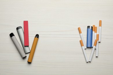Cigarettes with lighter and different vaping devices on white wooden background, flat lay. Smoking alternative