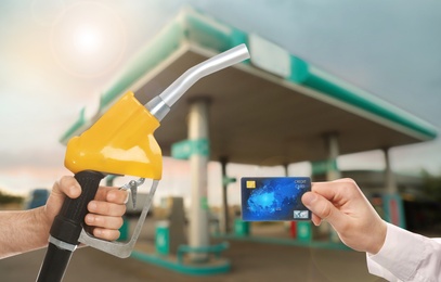 Image of Man holding credit card and worker with fuel nozzle at gas station, closeup. Cashless payment