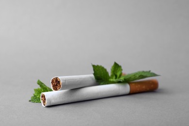 Photo of Menthol cigarettes and mint on grey background, closeup. Space for text