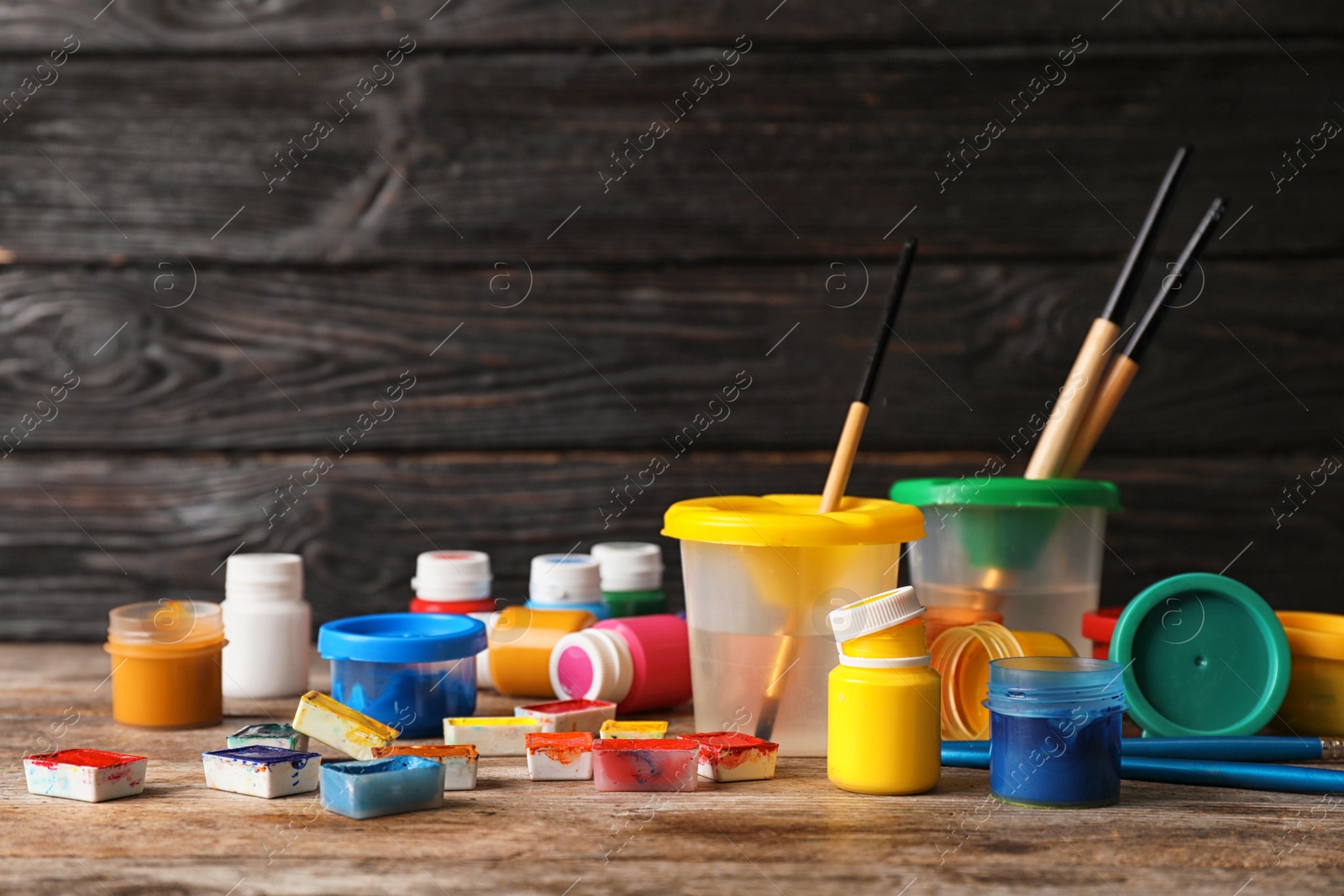 Photo of Set of child painting materials on table near wooden wall. Space for text