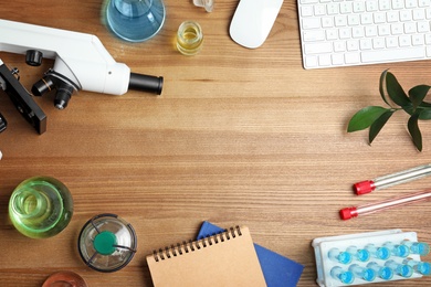 Flat lay composition with laboratory glassware, microscope and space for text on wooden background. Chemistry concept