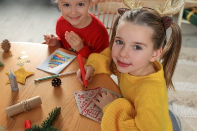 Cute little children making beautiful Christmas greeting cards at home