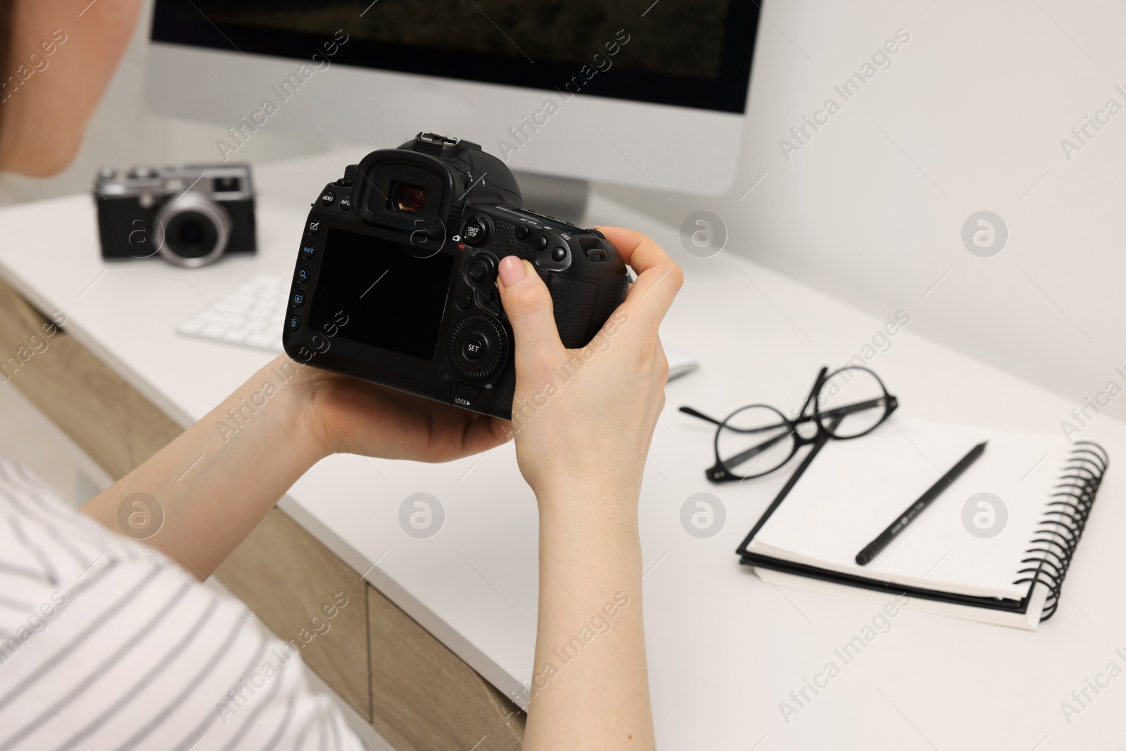 Photo of Photographer with camera at white table indoors, closeup