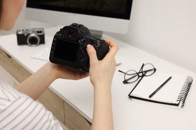 Photographer with camera at white table indoors, closeup