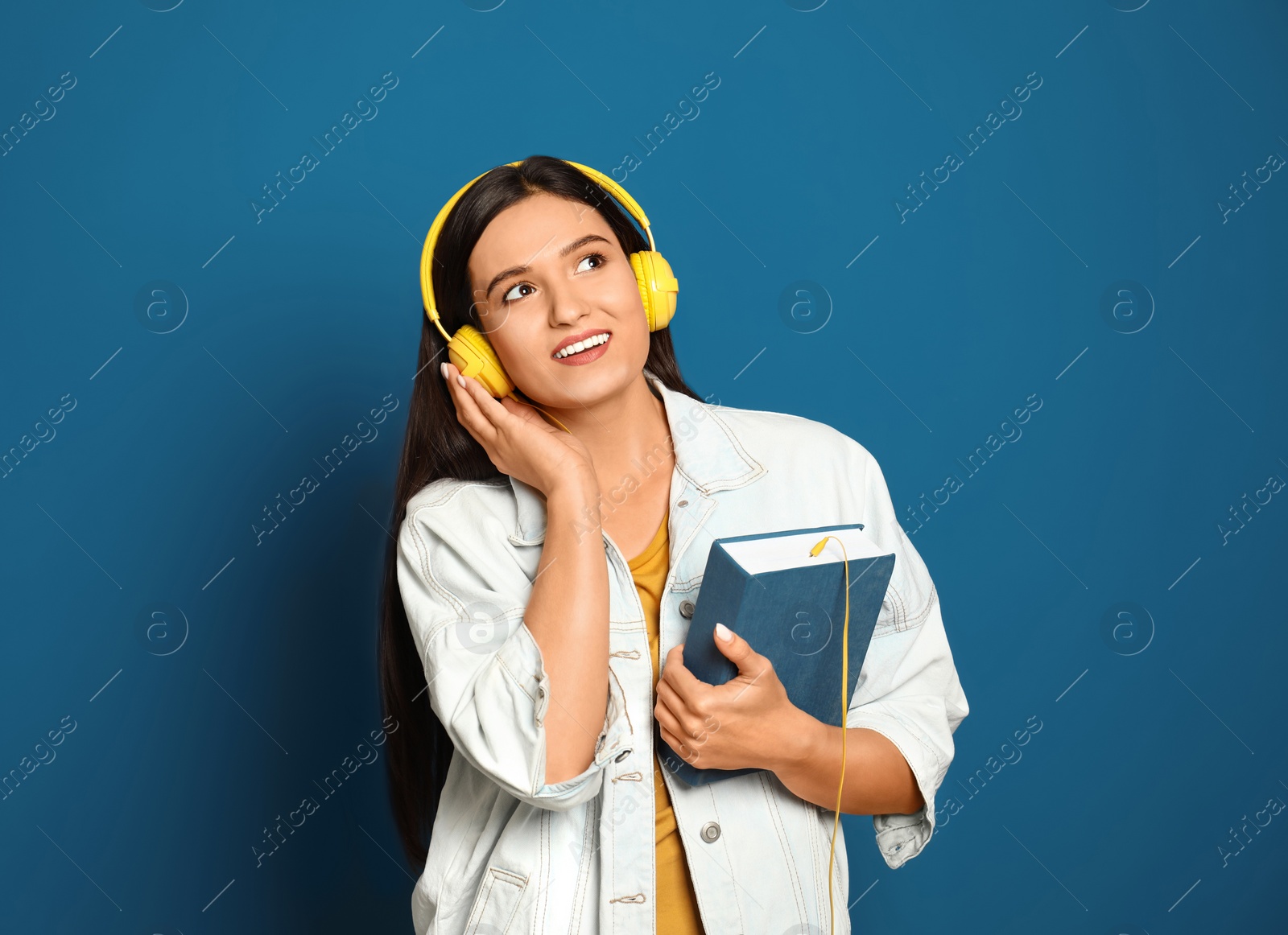 Photo of Young woman listening to audiobook on blue background