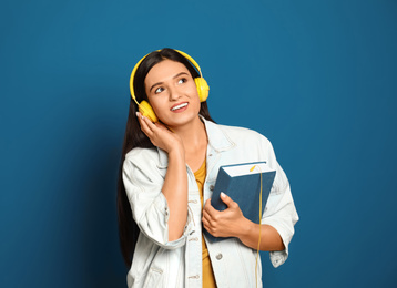 Young woman listening to audiobook on blue background