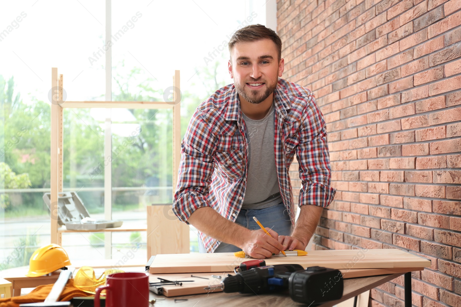 Photo of Young man working near brick wall indoors. Space for text