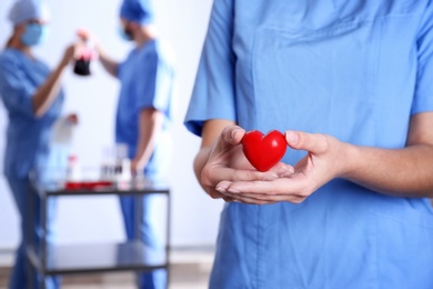 Photo of Doctor holding red heart at hospital, closeup. Donation day