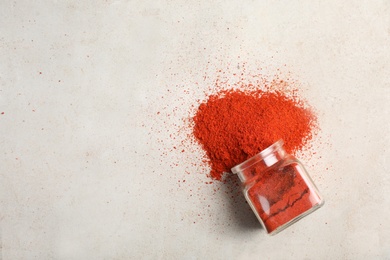 Photo of Glass jar with powdered red chili pepper and space for text on light background, top view