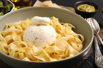 Photo of Delicious pasta with burrata cheese in bowl on table, closeup