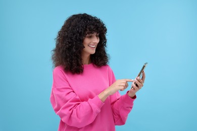Photo of Woman sending message via smartphone on light blue background, space for text