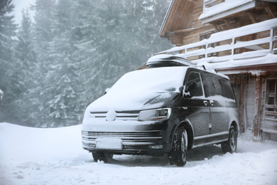 Modern car covered in snow outdoors on winter day