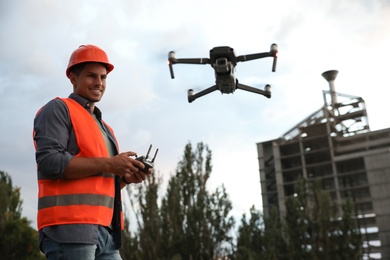 Builder operating drone with remote control at construction site. Aerial survey