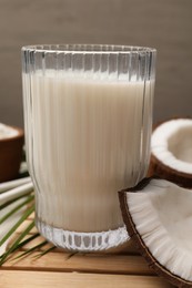 Photo of Glass of delicious vegan milk, coconuts and leaf on table, closeup