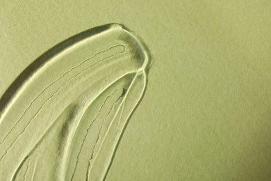 Photo of Sample of transparent cosmetic gel on olive background, top view. Space for text