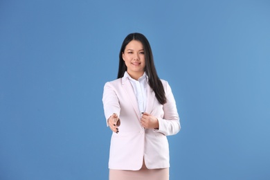 Business trainer reaching out for handshake on color background