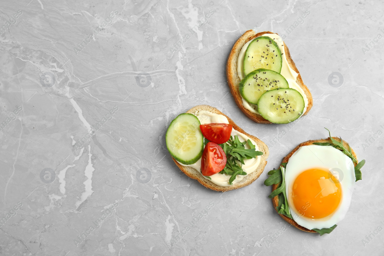 Photo of Slices of bread with different toppings on grey marble table, flat lay. Space for text