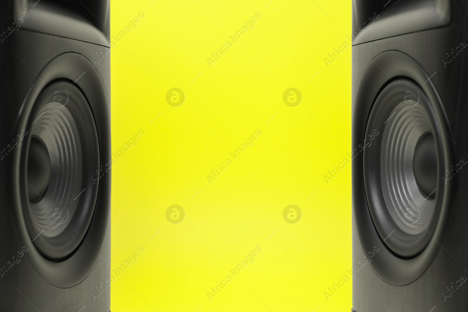 Photo of Wooden sound speakers on yellow background, closeup. Space for text