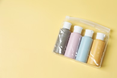 Photo of Cosmetic travel kit in plastic bag on yellow background, top view. Space for text