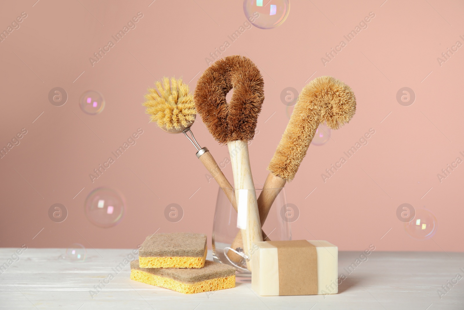 Photo of Cleaning supplies for dish washing and soap bubbles on pink background