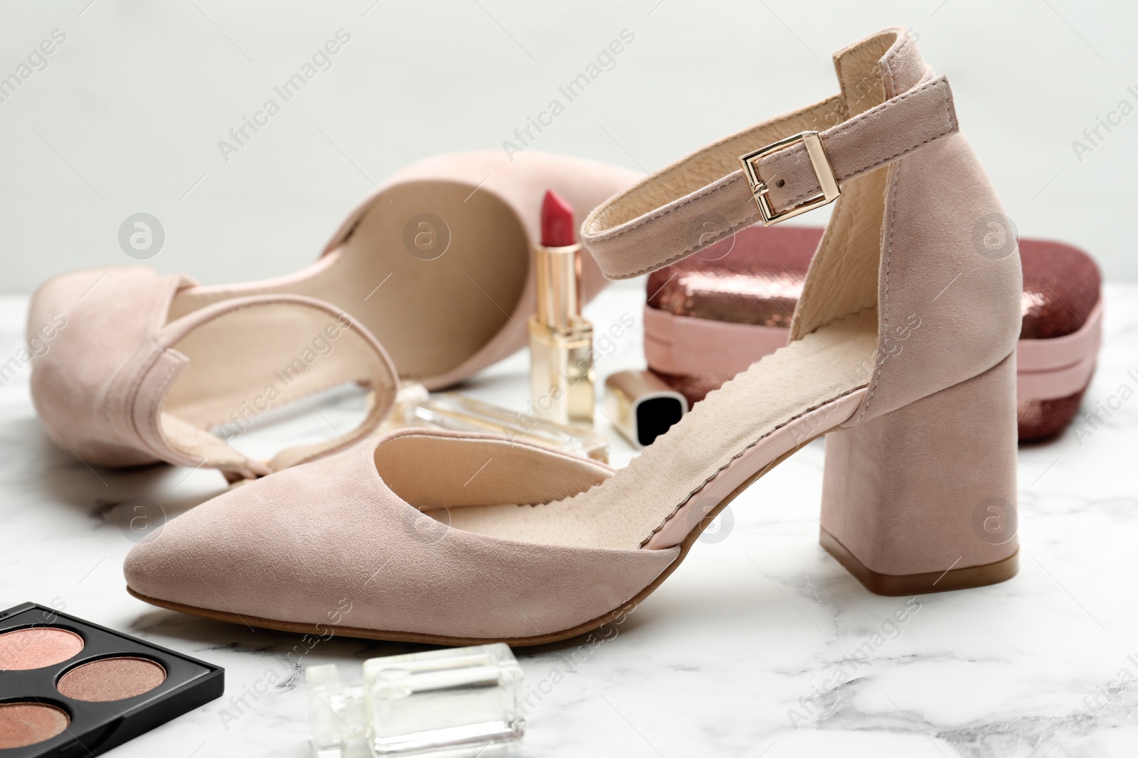 Photo of Stylish shoes and cosmetics on white marble table, closeup