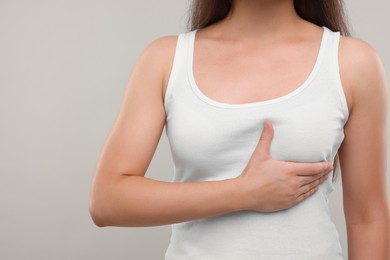Photo of Woman doing breast self-examination on light grey background, closeup