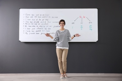 Happy English teacher near whiteboard at lesson