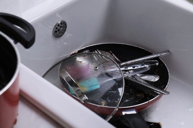 Photo of Many different dirty dishes and cutlery in sink