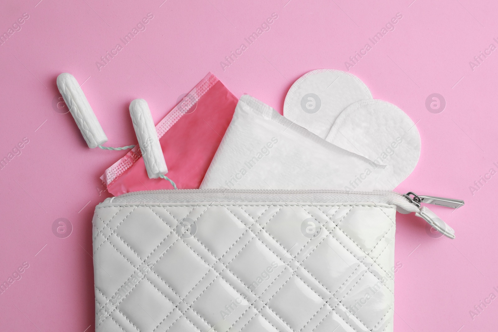 Photo of Bag with menstrual pads, tampons and pantyliners on pink background, flat lay