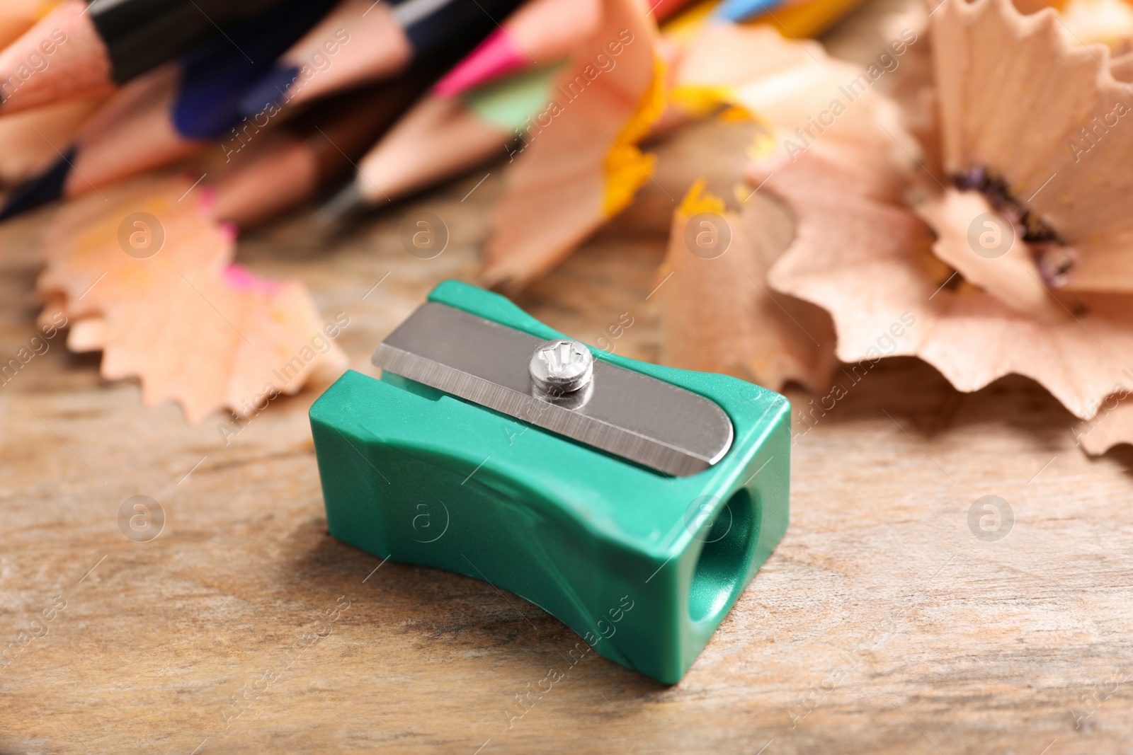 Photo of Turquoise sharpener, pencils and shavings on wooden table, closeup