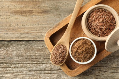 Photo of Caraway (Persian cumin) powder and dry seeds on wooden table, top view. Space for text