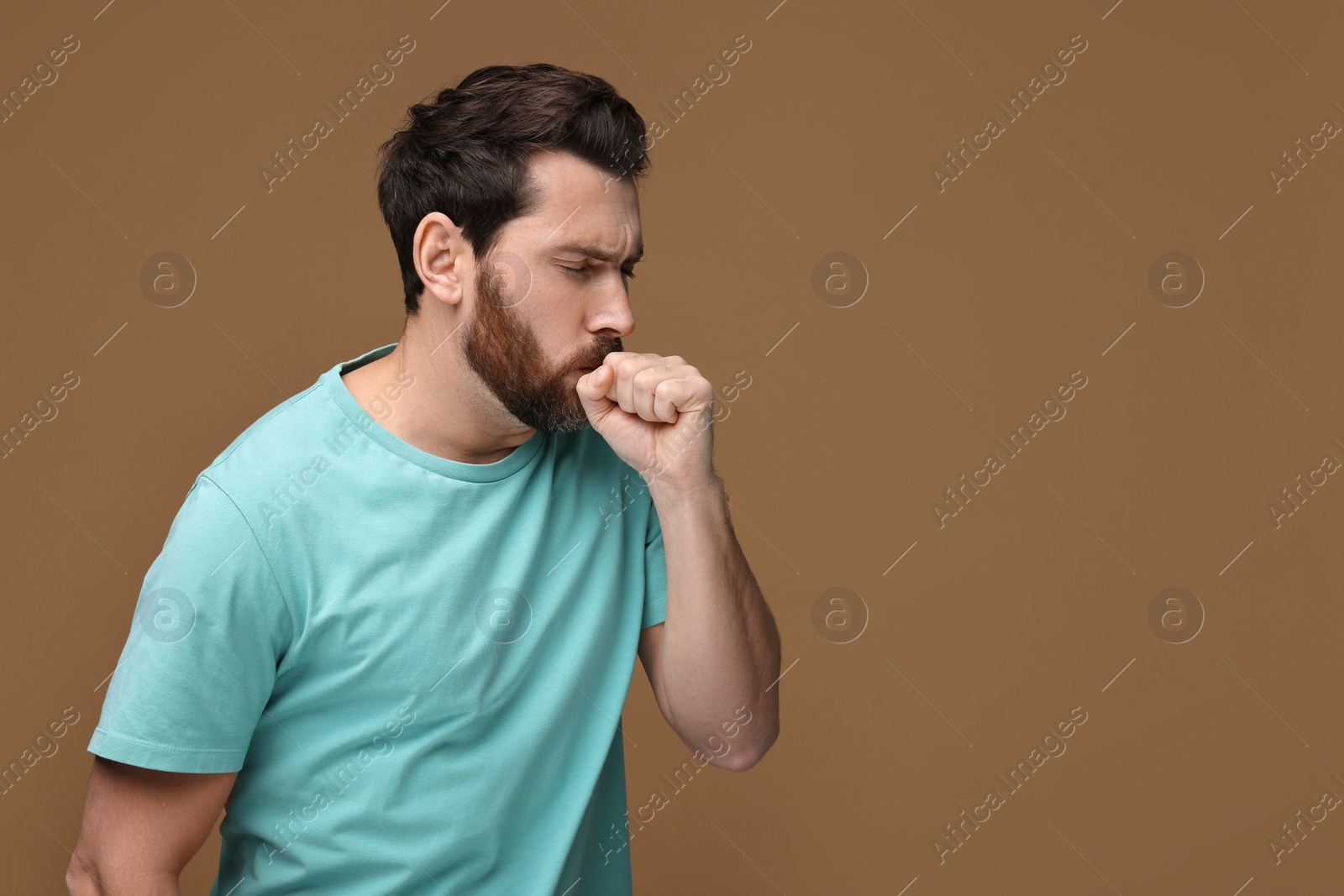 Photo of Sick man coughing on brown background, space for text. Cold symptoms